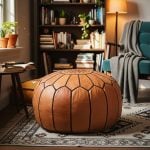 Tan leather round ottoman placed on a patterned rug in a cozy living room with bookshelves in the background.