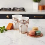 Close-up of white moroccan tea glasses showing geometric pierced silver metal filigree and opaque frosted glass