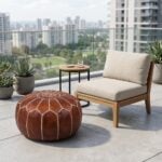 A brown leather round ottoman used as a versatile patio accessory on an outdoor balcony next to a lounge chair and side table.