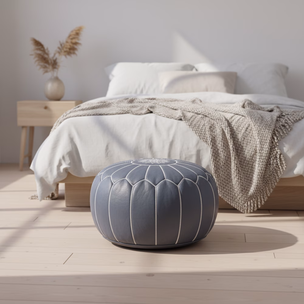 Leather Pouf Gray styled in a minimalist bedroom with white bedding and wooden furniture.