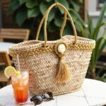 Gold straw bag on shelf, palm leaf woven tote with gold braided trim, tassel, and straw hat
