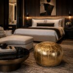 Gold leather round pouf styled in a luxury modern bedroom with dark wood paneling, upholstered bed, and warm ambient lighting.