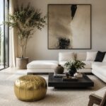 Gold leather round pouf showcased in a modern living room with a cream sectional sofa, oversized artwork, and neutral interior styling.