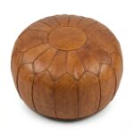 A high-quality tan round ottoman pouf made of genuine Moroccan leather, featuring a classic panel design on a white background.