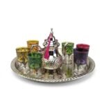 Professional studio shot of the MCTS06 silver moroccan tea set including a footed teapot and six multi-colored glasses on an engraved tray.