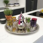 High-end silver moroccan tea set with a polished hammered finish displayed on a white marble kitchen island in a contemporary home.