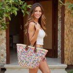Woman carrying Sequin Straw Bag with multicolor confetti weave and brown leather straps outdoors