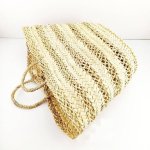 Handwoven straw basket bag side angle displaying decorative lattice stripes and natural fiber texture