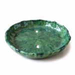Angled view of artisan-made green Tamegroute ceramic plate showing depth and handcrafted details