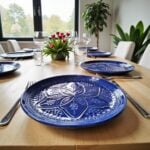 Blue geometric ceramic plates with raised relief pattern set on modern dining table with wine glasses