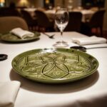 Olive green geometric ceramic plate with intricate relief pattern on elegant restaurant table setting