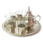 Silver hammered tea set with ornate teapot, 6 glass holders, and decorative serving tray on white background
