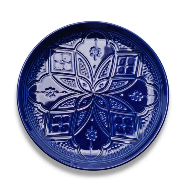 Navy blue geometric ceramic plate close-up, intricate hand-engraved relief mandala pattern glaze finish