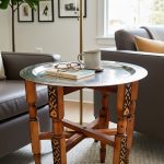 Hammered silver tea tray table as living room coffee table with books, coffee cup, and glasses in contemporary neutral space