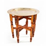 Hand hammered brass tea tray table with gold finish and carved wooden folding stand shown on white background product photo