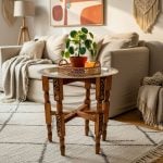 Hand hammered silver tea tray table in boho living room with carved wooden stand, wicker basket, plant and candle styling