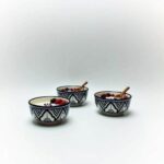 Three hand-painted ceramic serving bowls with black Zwak patterns filled with berries and spoons
