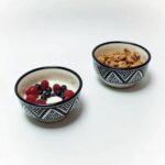 Two food-safe ceramic serving bowls with geometric patterns holding yogurt and granola