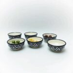 Six hand-painted ceramic serving bowls with traditional Zwak patterns displayed with various foods