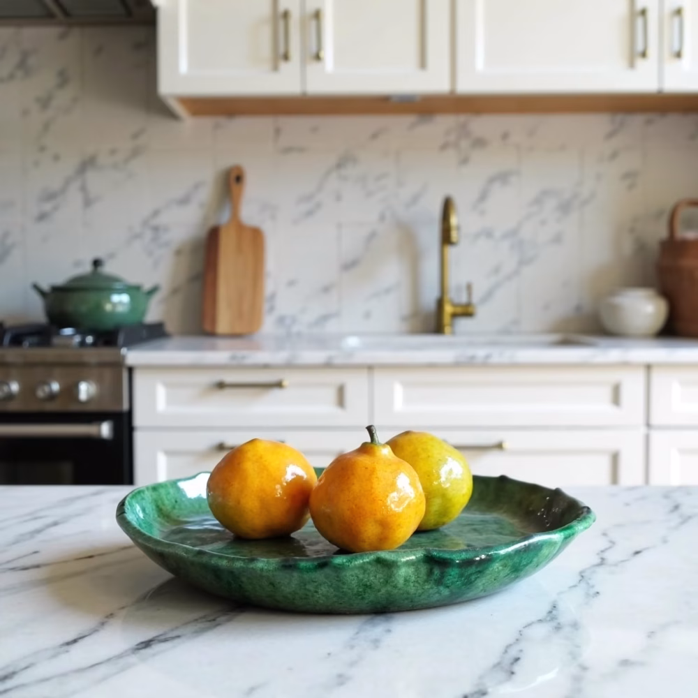 Handmade green Tamegroute ceramic plate with scalloped edges displayed in modern white kitchen with fruit