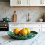 Moroccan Tamegroute ceramic plate holding yellow fruits on marble counter, showcasing emerald green glazed finish