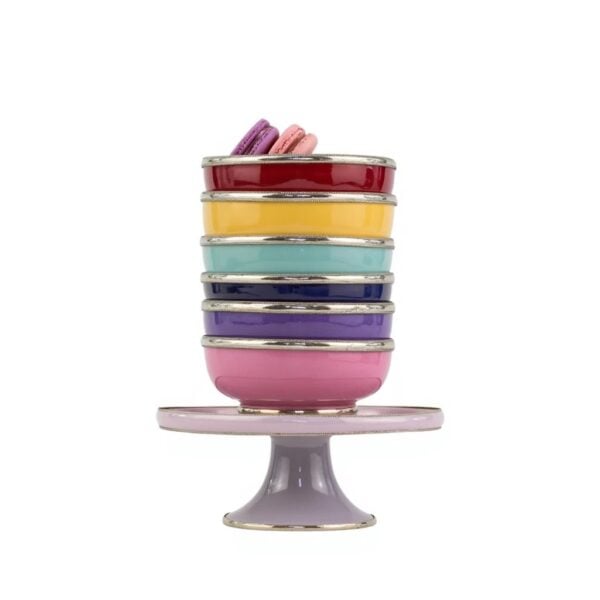 Stacked ceramic bowls with silver trim on pedestal, topped with purple and pink macarons