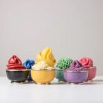 Colorful ceramic bowls with silver trim filled with decorative piped frosting in various colors