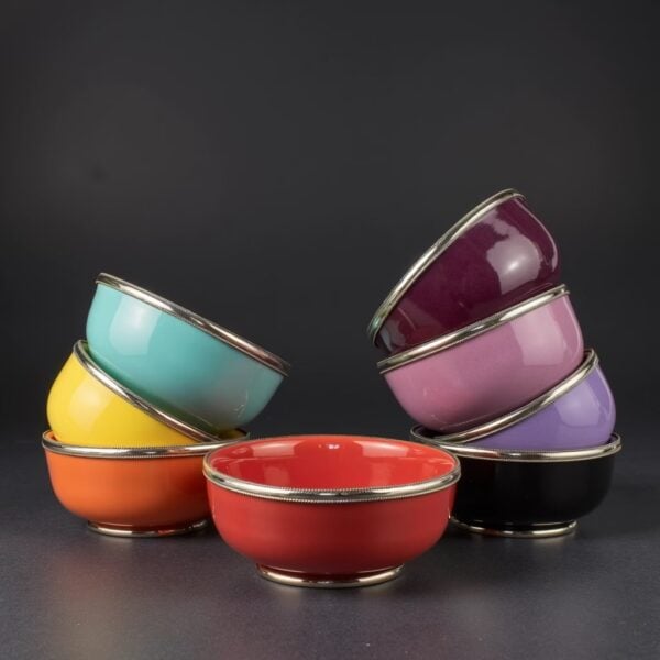 Stacked ceramic bowls with silver trim displaying red, yellow, turquoise, pink and purple colors on black