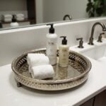 Silver tray with feet organizing bath products and white towels on bathroom vanity countertop