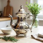Detailed geometric grid panel on hamsa silver teapot moroccan with ornate curved handle in kitchen setting