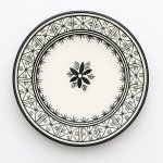 Hand-painted ceramic plate with black Moroccan geometric patterns and floral center on cream background