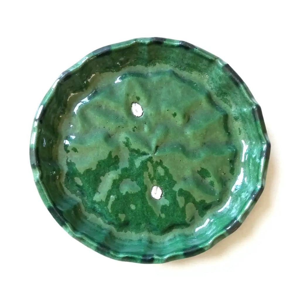 Top view of handmade Moroccan Tamegroute handmade ceramic plate with unique green glazing and scalloped edge Handmade green Tamegroute ceramic plate with scalloped edge showing mottled emerald glaze and artisan craftsmanship