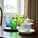 Set of six multicolor jewel-tone filigree tea glasses featuring intricate silver wire-wrapping and chain sleeves