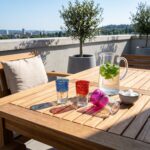 Moroccan Colored Glass Tea Cups casting colorful shadows on a wooden patio table in a sunny outdoor setting, styled with a pitcher of fresh mint water and sugar cubes.