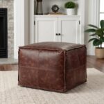 Square leather ottoman in tan brown showing soft cushioned top and contrast stitching detail