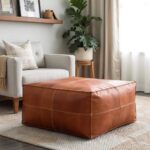 Tan square leather ottoman in boho living room with floating shelves and natural textiles