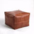 Product shot of square natural pouf showing cross-stitch detail