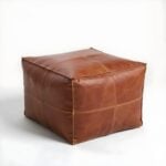 Square leather ottoman pouf in tan brown with visible stitching detail on white background