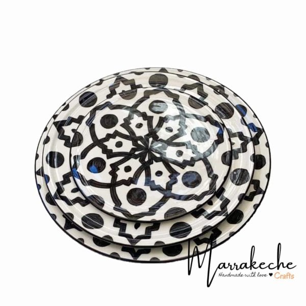 Hand-painted ceramic plates set stacked showing black geometric patterns and dots on white dinnerware