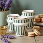 Hand-decorated ceramic tea cups with sage green pattern and 12-carat gold trim with macarons