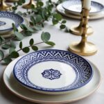 Blue ceramic plates with ornate patterns styled on elegant table setting with brass candlesticks and eucalyptus