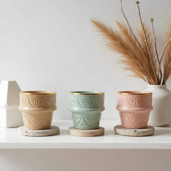 Hand-decorated ceramic espresso cups in beige, mint, and pink with gold rims on stone coasters