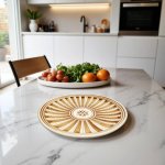 Golden brown hand-painted ceramic plate with sunburst design and central floral motif on marble counter