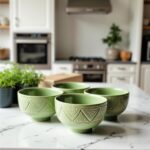 Set of four green geometric ceramic bowls with detailed textured patterns on kitchen counter