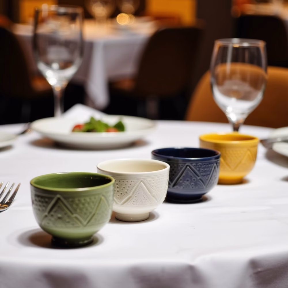 Set of 4 hand-engraved ceramic bowl collection in green, yellow, blue and white displayed in various settings