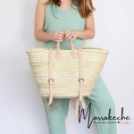 Handwoven convertible straw backpack with light leather straps held by woman in mint green outfit