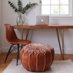 Brown leather pouf ottoman with embroidered design in home office