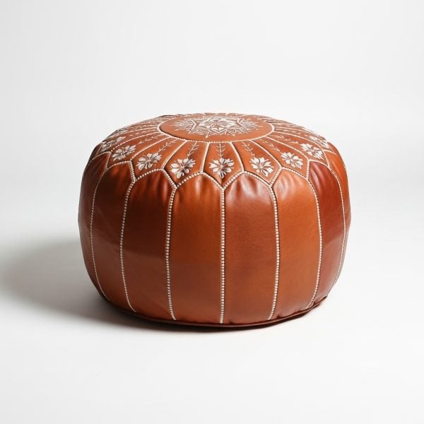 Studio shot of a light brown leather floor ottoman featuring decorative white stitching isolated on a white background.