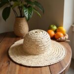 Flat lay handwoven straw hat on wooden table, wide brim spiral crown design, natural home decor