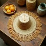 Handwoven straw garden hat with fringe on wooden chair, natural beige color, outdoor garden accessory